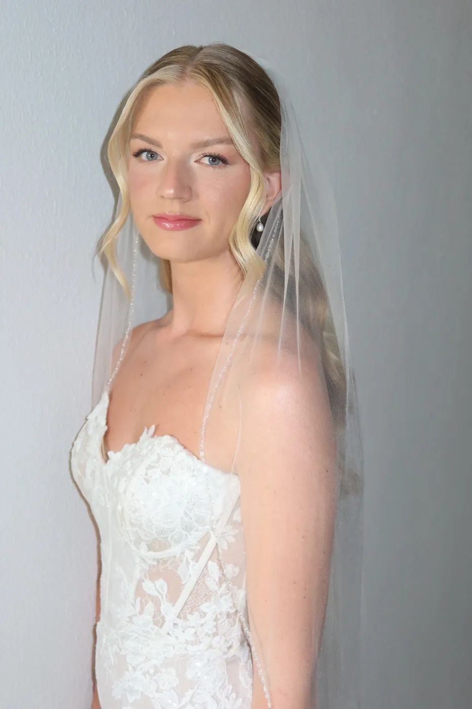 Novia rubia con velo transparente y piel suave y luminosa