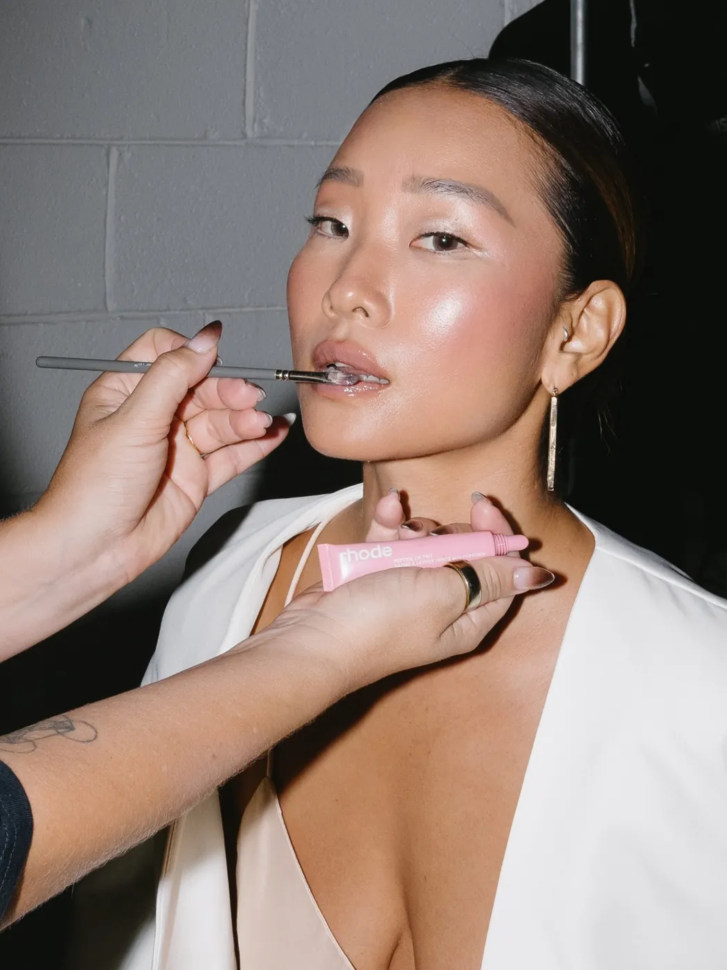 Zoë Elizabeth aplicando color de labios a una modelo con chongo pulido