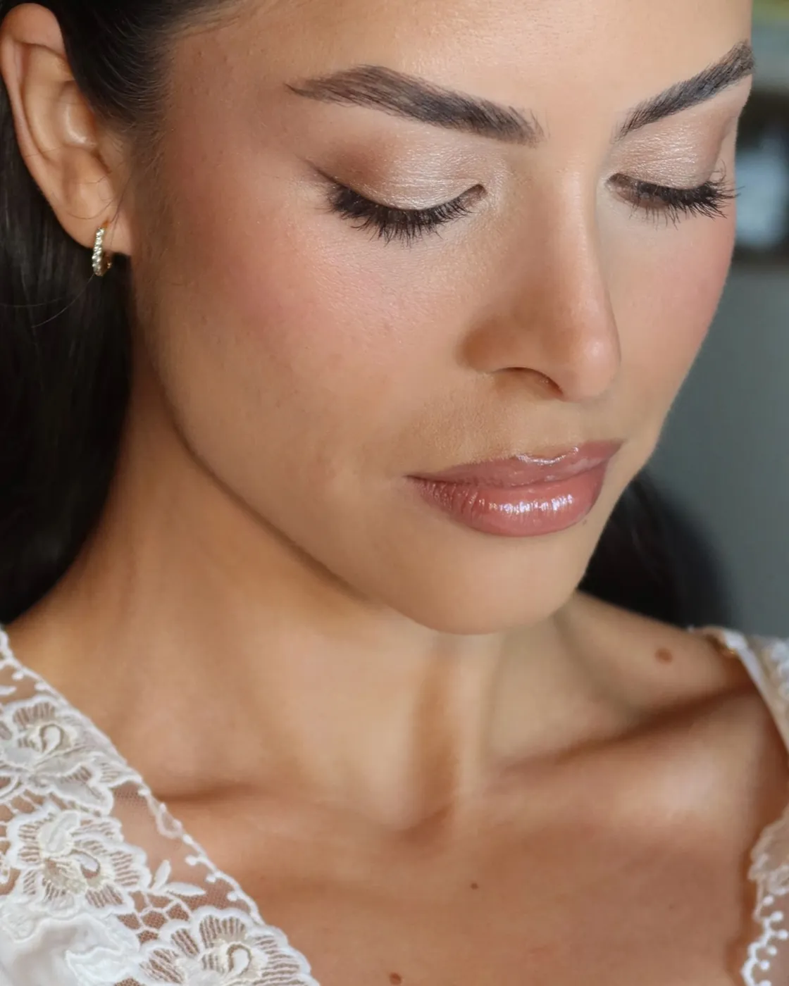 Novia en bata de encaje con párpado bronce suave y piel luminosa