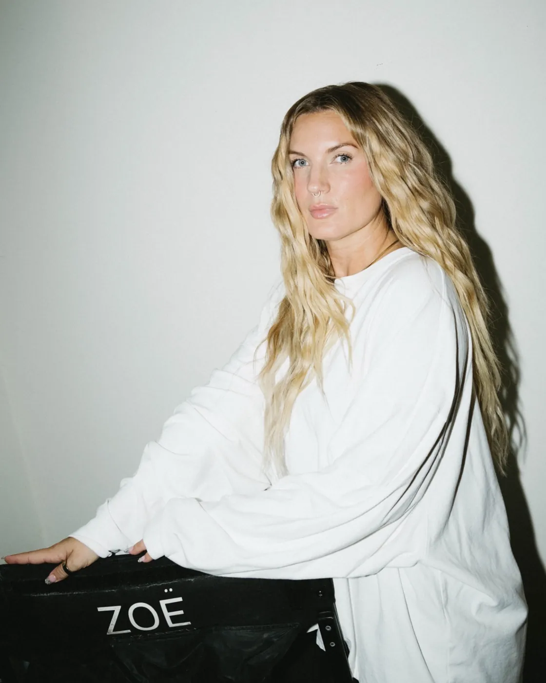 Zoë Elizabeth sentada junto a su silla de directora con una sudadera blanca